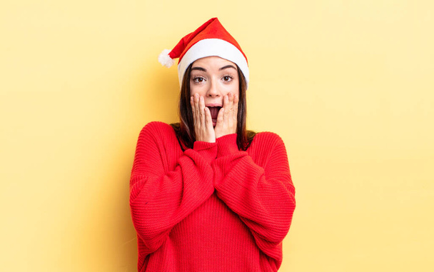 young hispanic woman feeling shocked and scared. chistmas and new year concept - Фото, изображение