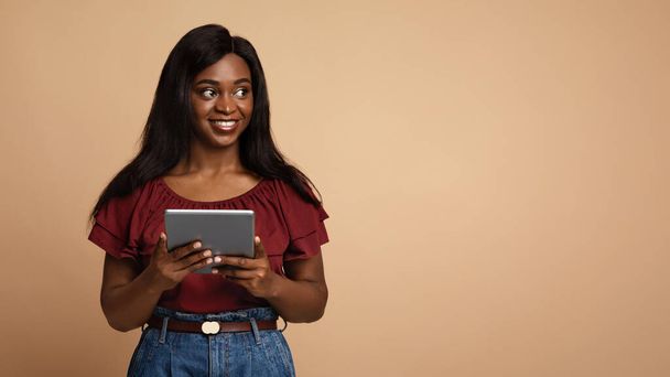 Pretty black woman with digital tablet looking at copy space - Foto, immagini