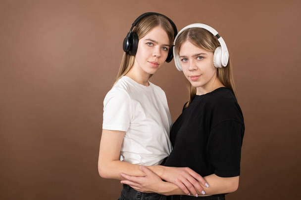 Two teenage girls in headphones and t-shirts standing close to one another - Photo, Image