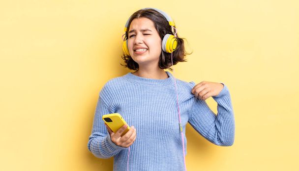 young hispanic woman feeling stressed, anxious, tired and frustrated. headphones and smartphone concept - Фото, изображение