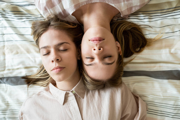 Väsynyt teini kaksoset tytöt koskettaa heidän kasvonsa nukkuessaan - Valokuva, kuva