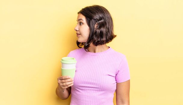 young hispanic woman on profile view thinking, imagining or daydreaming. take away coffee concept - Φωτογραφία, εικόνα