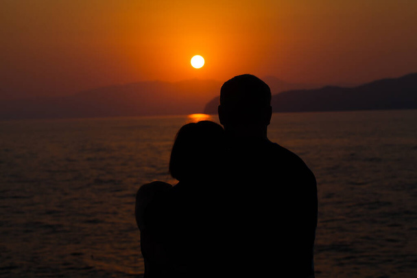 夕日の空に立って魅力的な若い男と女.ロマンチックなカップルと日没 - 写真・画像