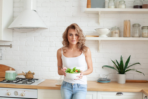 Belle femme blonde tenant bol avec salade de légumes verts - Photo, image