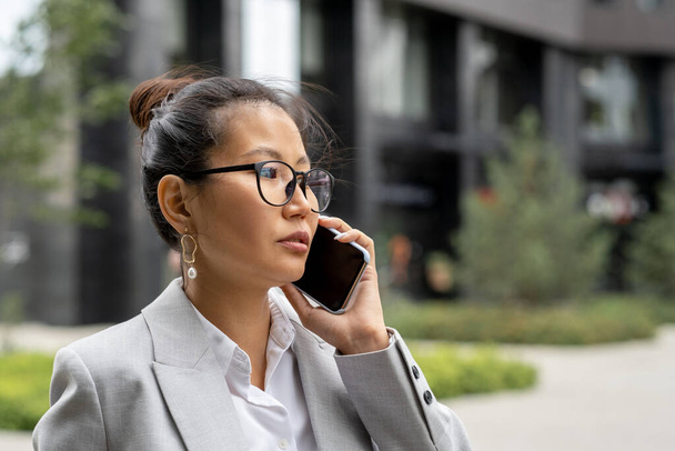 Young serious Asian businesswoman calling business partner - Fotoğraf, Görsel
