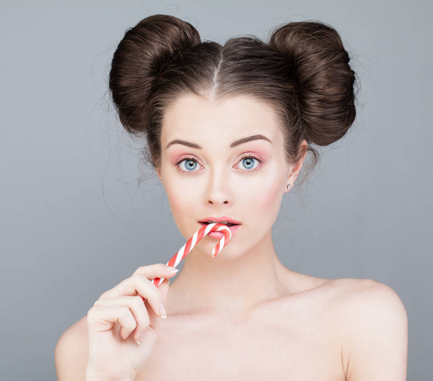 Hermosa mujer con maquillaje de ojo rosa sosteniendo dulces dulces  - Foto, Imagen