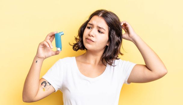 young hispanic woman feeling puzzled and confused, scratching head. asthma concept - Фото, изображение
