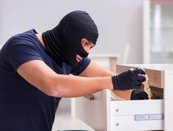 Robber wearing balaclava stealing valuable things - Foto, Bild