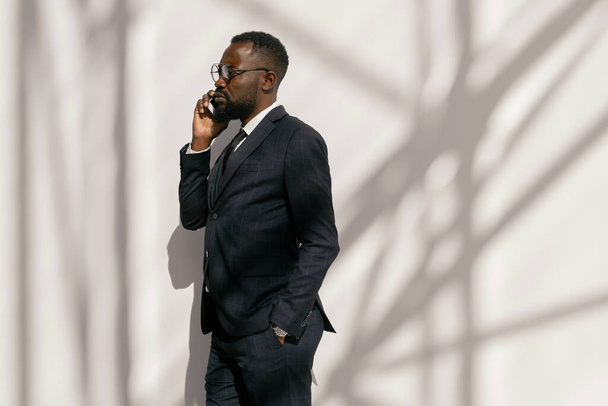 Side view of serious businessman with smartphone by ear - Zdjęcie, obraz
