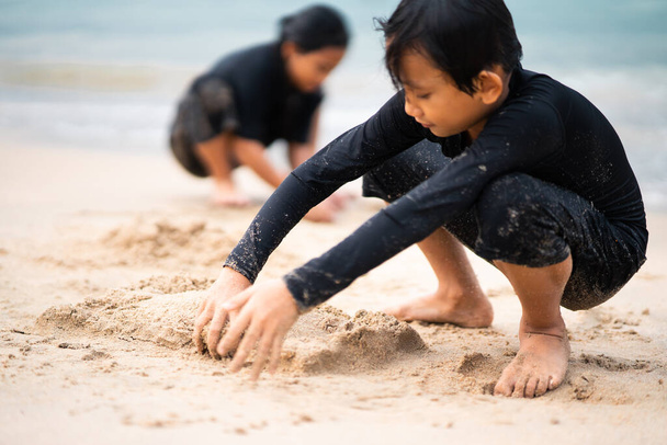 Jovens asiáticos crianças estão jogando na praia. Conceito de férias e relaxamento. - Foto, Imagem