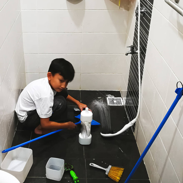 Asiático chico lavado en el baño.Él se está divirtiendo en ayudar a sus padres con las tareas domésticas. - Foto, imagen