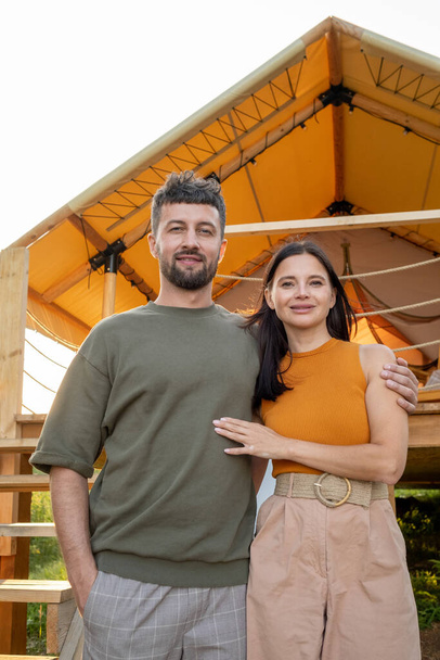 Happy young couple standing against glamping tent - Photo, Image