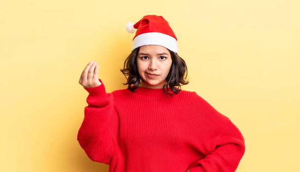 young hispanic woman making capice or money gesture, telling you to pay. christmas concept - Фото, изображение