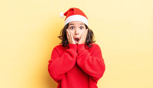 young hispanic woman feeling shocked and scared. christmas concept - Foto, Imagen
