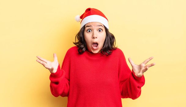 young hispanic woman feeling extremely shocked and surprised. christmas concept - Photo, image