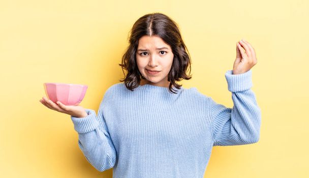 young hispanic woman making capice or money gesture, telling you to pay. empty bowl concept - Foto, imagen