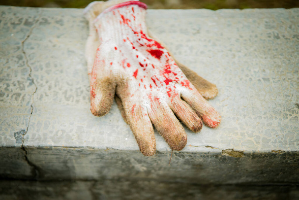 Vleeshandschoenen met bloedvlekken op het beton. - Foto, afbeelding