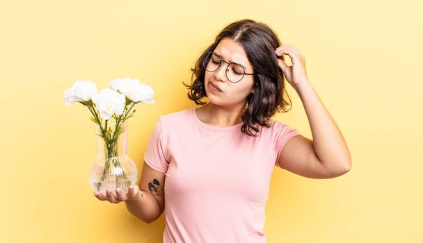 young hispanic woman smiling happily and daydreaming or doubting. flowers pot concept - Foto, Imagem