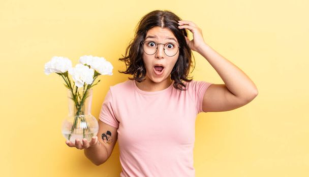 young hispanic woman looking happy, astonished and surprised. flowers pot concept - Foto, Imagen