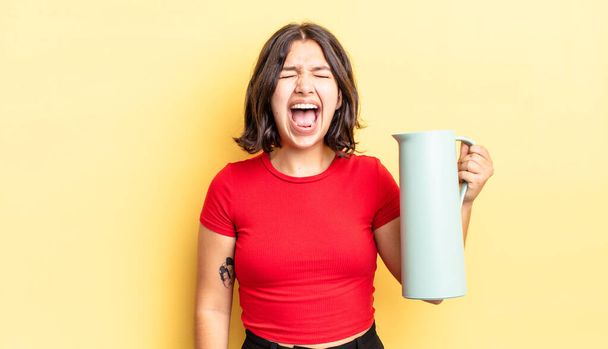 young hispanic woman shouting aggressively, looking very angry. thermos concept - Fotoğraf, Görsel
