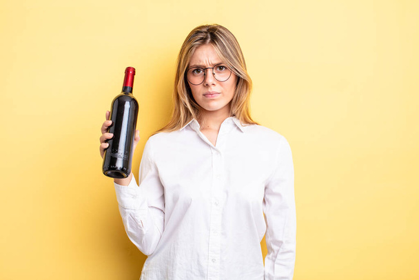 pretty blonde girl feeling sad, upset or angry and looking to the side. wine bottle concept - Fotó, kép