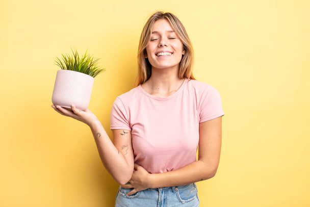 pretty blonde girl laughing out loud at some hilarious joke. houseplant concept - Photo, Image