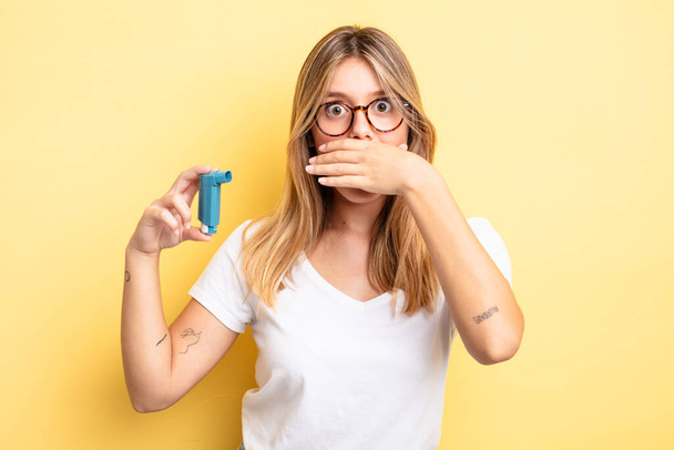 pretty blonde girl covering mouth with hands with a shocked. asthma inhaler concept - Fotoğraf, Görsel
