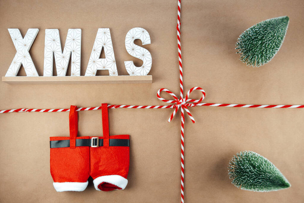 Χριστουγεννιάτικο κορδόνι ή σπάγκο δεμένο σε φιόγκο σε χάρτινο φόντο Κραφτ με χριστουγεννιάτικο σήμα και Άγιο Βασίλη - Φωτογραφία, εικόνα