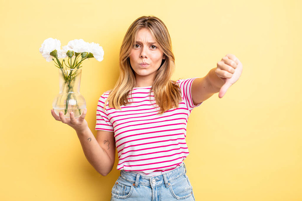 pretty blonde girl feeling cross,showing thumbs down. decorative flowers concept - Foto, Imagem
