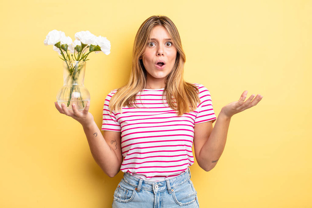 pretty blonde girl feeling extremely shocked and surprised. decorative flowers concept - Foto, immagini