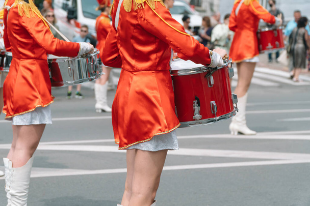 Young girls drummer in red vintage uniform at the parade. Street performance of festive march of drummers girls in red costumes on city street - Foto, Imagem
