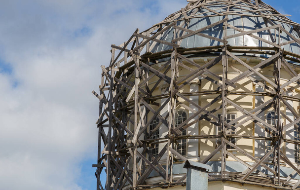 andamios de madera gris en la cúpula arquitectónica a la luz del día en el cielo azul con nubes blancas - Foto, Imagen
