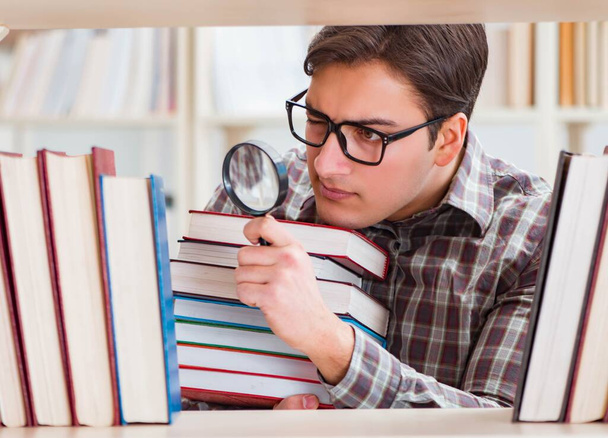 Νεαρός φοιτητής ψάχνει για βιβλία στη βιβλιοθήκη του κολεγίου - Φωτογραφία, εικόνα