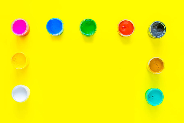 Cans of multi-colored paint are located on the side and on top of the photo on a yellow background. top view, flat lay, copy space, isolate. - Fotografie, Obrázek