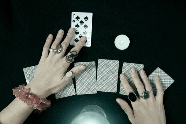 Fortune teller or witch hands, cards, candles and a glowing magic ball. Halloween, magic and tricks concept - Foto, Imagen