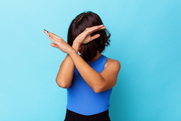 Young mixed race woman isolated on blue background keeping two arms crossed, denial concept. - Foto, Imagen
