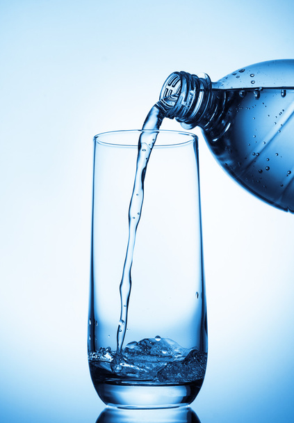 наливая воду в стекло из бутылки - Фото, изображение