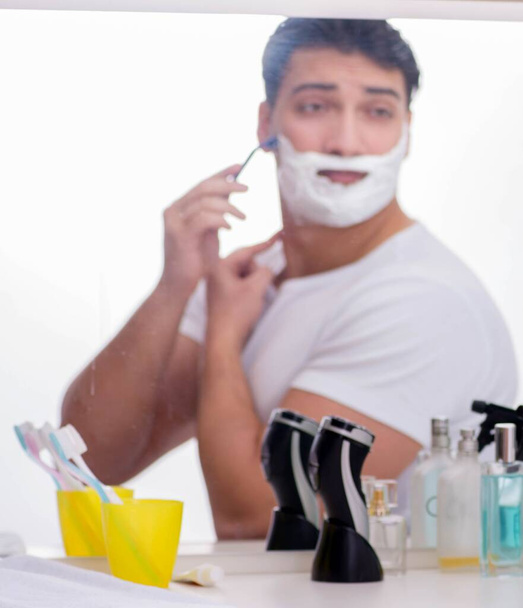 Молодий красивий чоловік голиться вранці
 - Фото, зображення