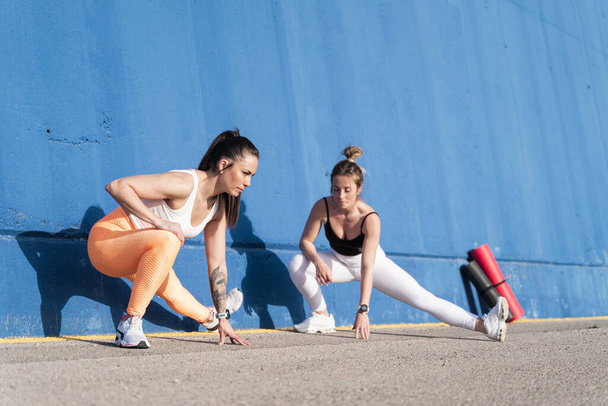 Formda genç bayan arkadaşlar sabahları esneme egzersizi yapıyorlar. Spor yapan kadınlar dışarıda egzersiz yapıyor. - Fotoğraf, Görsel