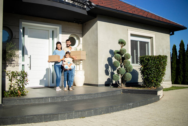 Πορτρέτο της ευτυχισμένης καυκάσιας οικογένειας που στέκεται στη βεράντα του νέου τους σπιτιού έτοιμο να μετακομίσει. - Φωτογραφία, εικόνα