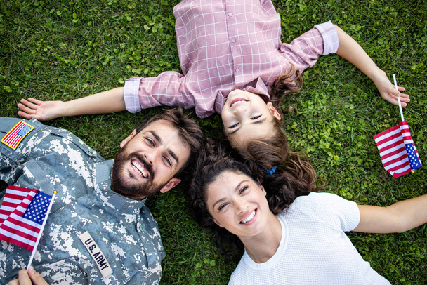 Top zicht van militaire familie liggend op het gras tijd doorbrengen samen met soldaat thuiskomen. - Foto, afbeelding