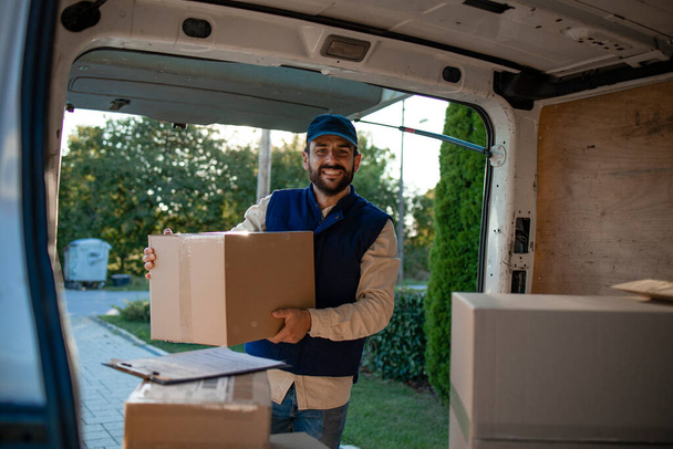 Portrait of mailman holding packages by his van. - Φωτογραφία, εικόνα