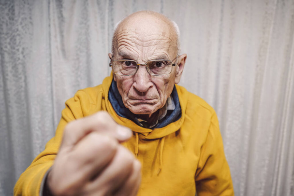 Portrait of angry caucasian man wearing eyeglasses and showing fist - 写真・画像