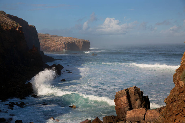 Прочная природная зона вдоль побережья с острыми скалами, крутыми скалами, низкорастущим подлеском и скрытыми участками пляжа, высокие волны ломаются и плескаются на побережье - Фото, изображение
