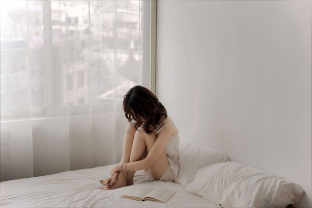 Молодая женщина лежит на кровати и читает книгу
 - Фото, изображение