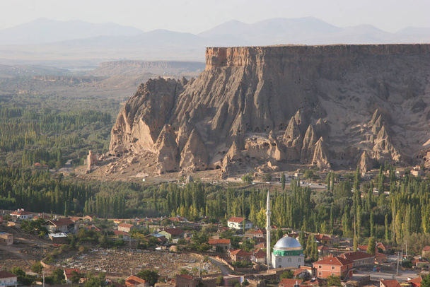 Jellemző cappadociai völgy falu mellett erodált hegy történelmi szikla lakások és templomok faragott kövek - Fotó, kép