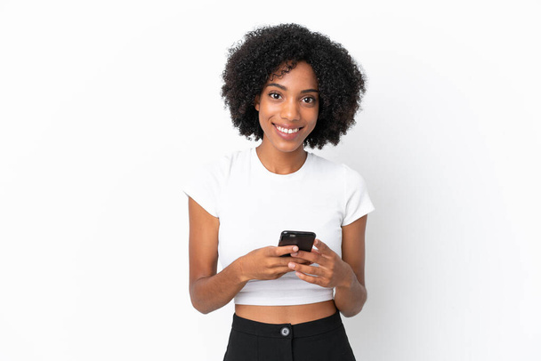 Молодая афроамериканка, изолированная на белом фоне, отправляет сообщение с мобильного телефона - Фото, изображение