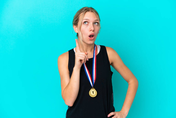 Young caucasian woman with medals isolated on blue background thinking an idea pointing the finger up - Photo, image