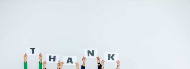 Студійний знімок невизначеної групи співробітників у корпоративному офісі, що тримає знак подяки за алфавіт картонного паперу над головою, що демонструє вдячність клієнту на білому тлі
. - Фото, зображення
