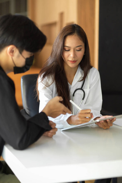 Médico femenino registra el historial de alergia a medicamentos de la paciente en una tableta digital en la sala de examen  - Foto, imagen